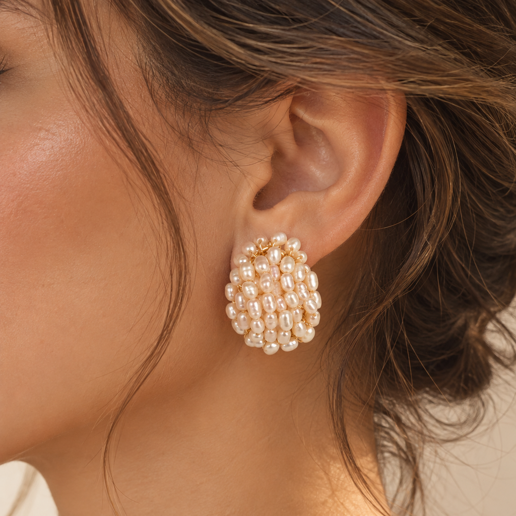 A close-up of a model's ear wearing a cluster of gold and pearl stud earrings.
